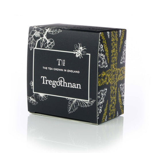 Elegant Tregothnan tea box with botanical and bee design, against a reflective surface.